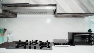 A kitchen with a gas stove, a built-in oven, and a toaster oven.
