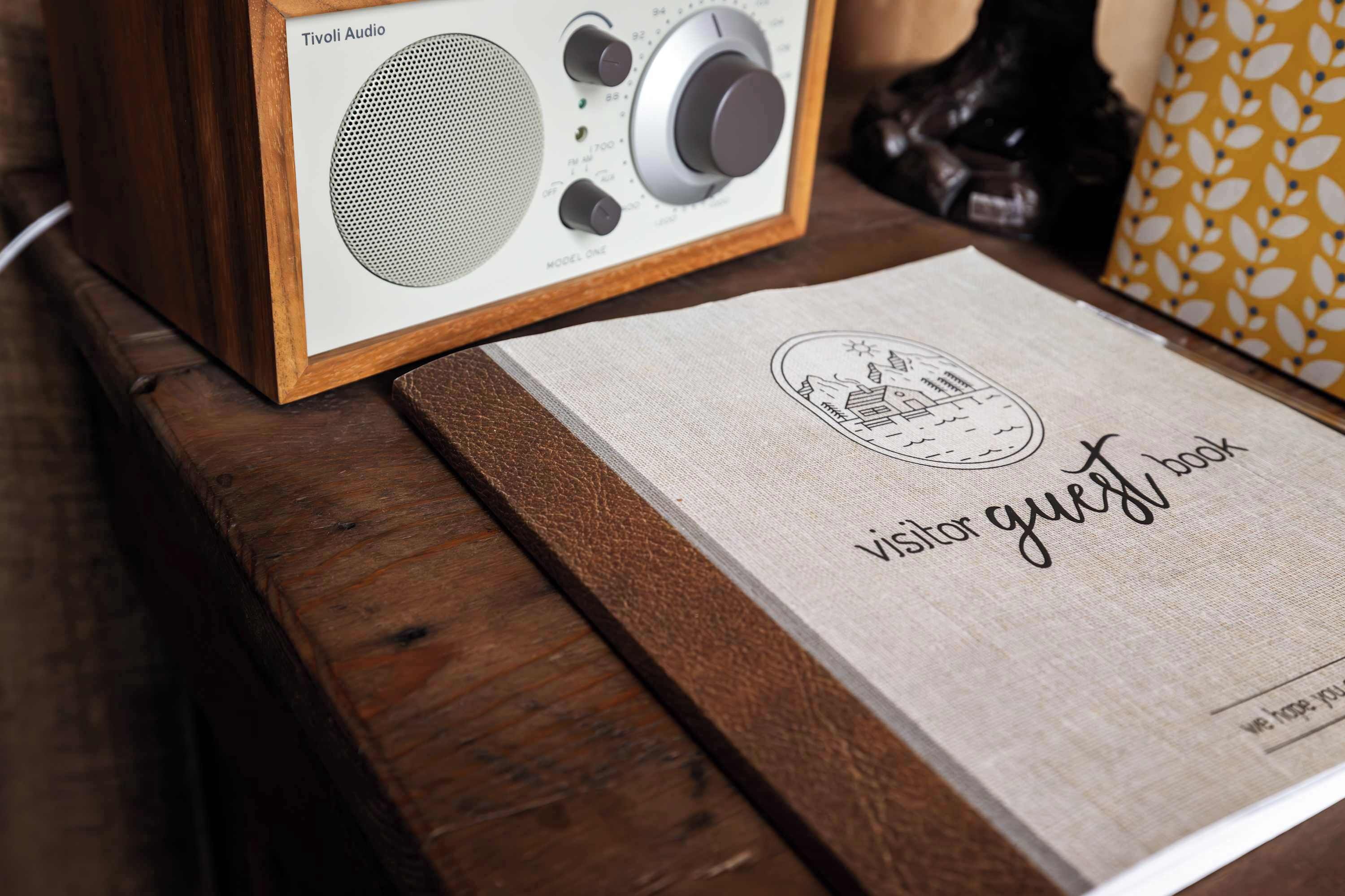 A framed radio on a wooden surface with a visitor guest book beside it.