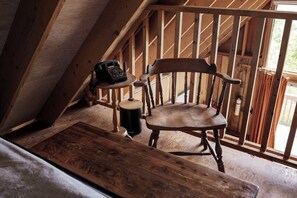 Una silla de madera en una habitación con techo inclinado y una ventana.