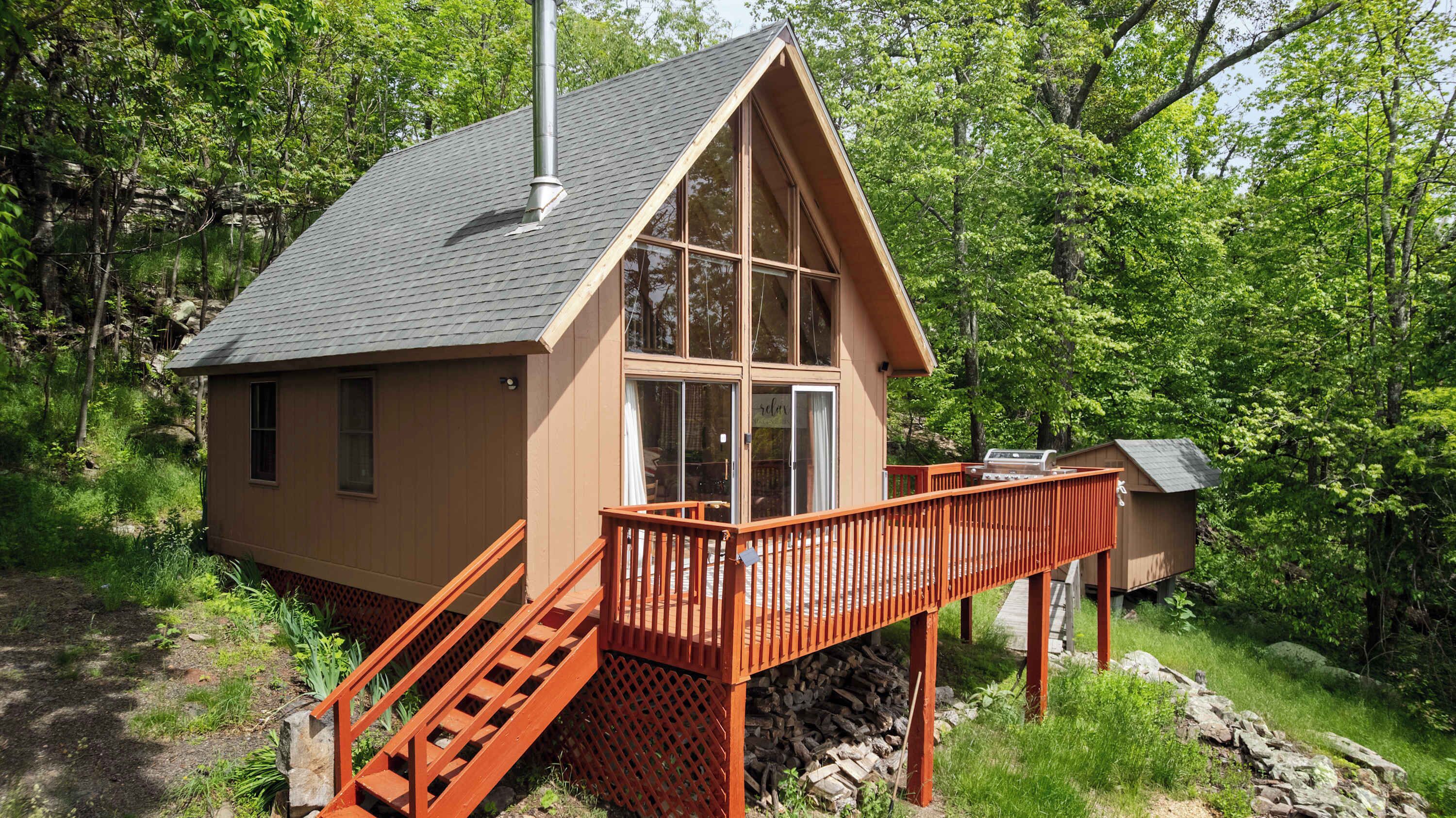 A cabin with a deck, a chimney, and a small outdoor grill area.