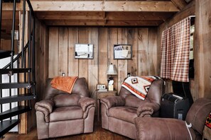 Una habitación acogedora con dos sillones de cuero, una mesita con una lámpara y un radio.