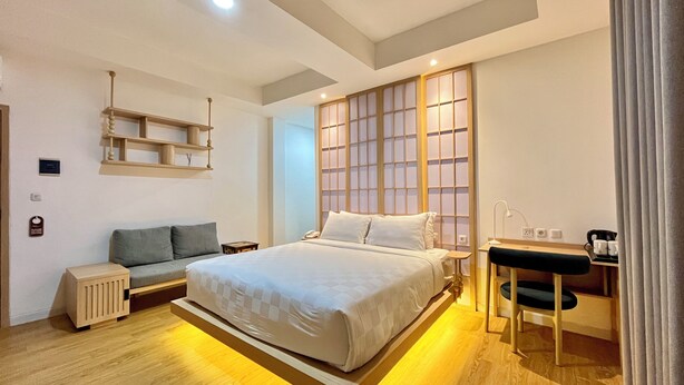 Une chambre d’hôtel moderne, dotée d’un grand lit, d’un bureau, d’un canapé et d’un paravent japonais.