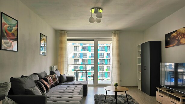 Un salon moderne avec un canapé d’angle, un téléviseur et une petite table.