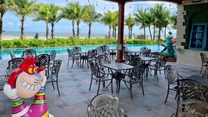 Eine Außenpatio mit Pool, umgeben von Palmen und Blick auf den Strand.