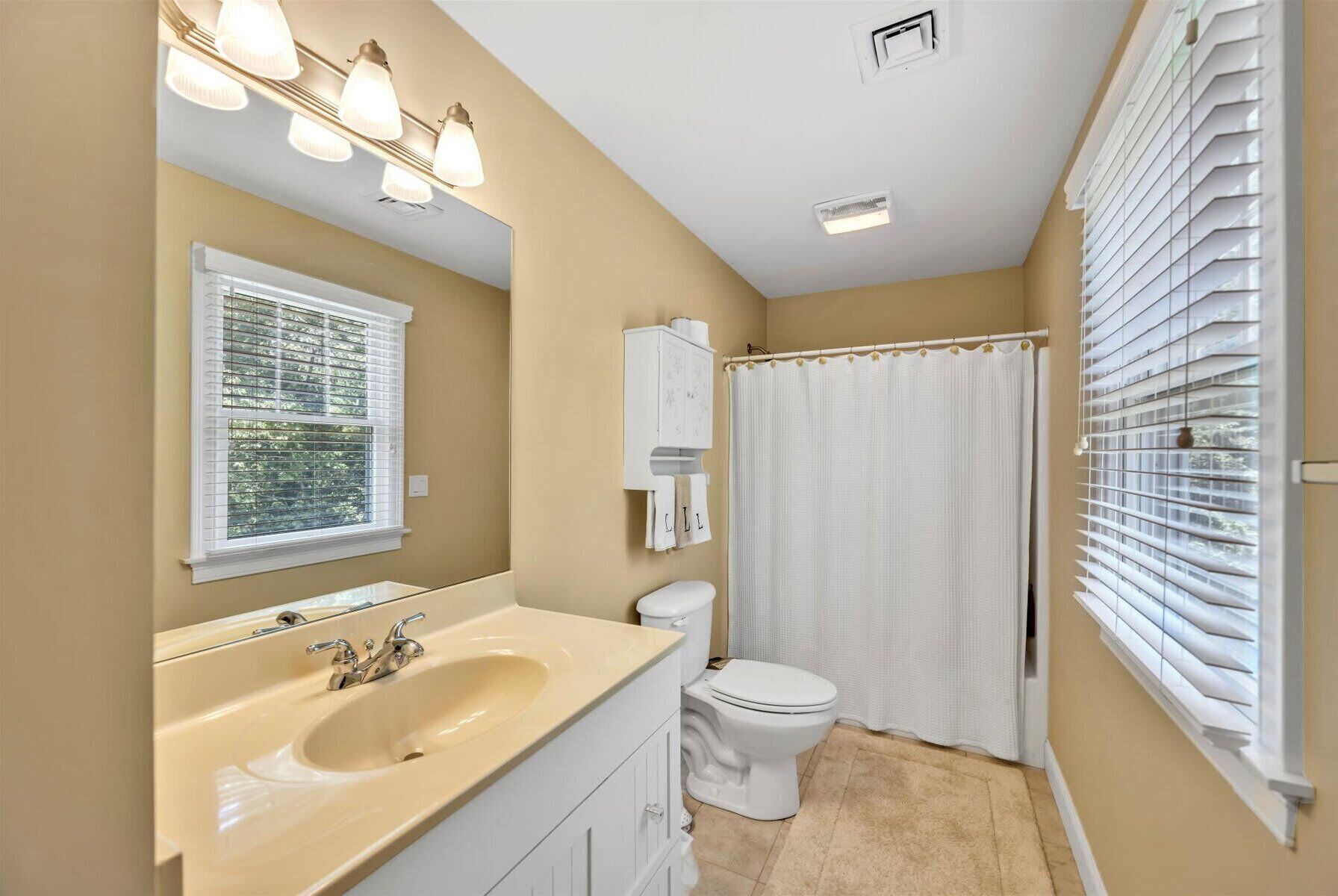 A bathroom with a sink, toilet, and shower curtain.