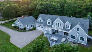 A large, two-story house with a covered patio and a driveway. - 7BR Estate · One Block to Ocean · Sleeps 22 (Falmouth)
