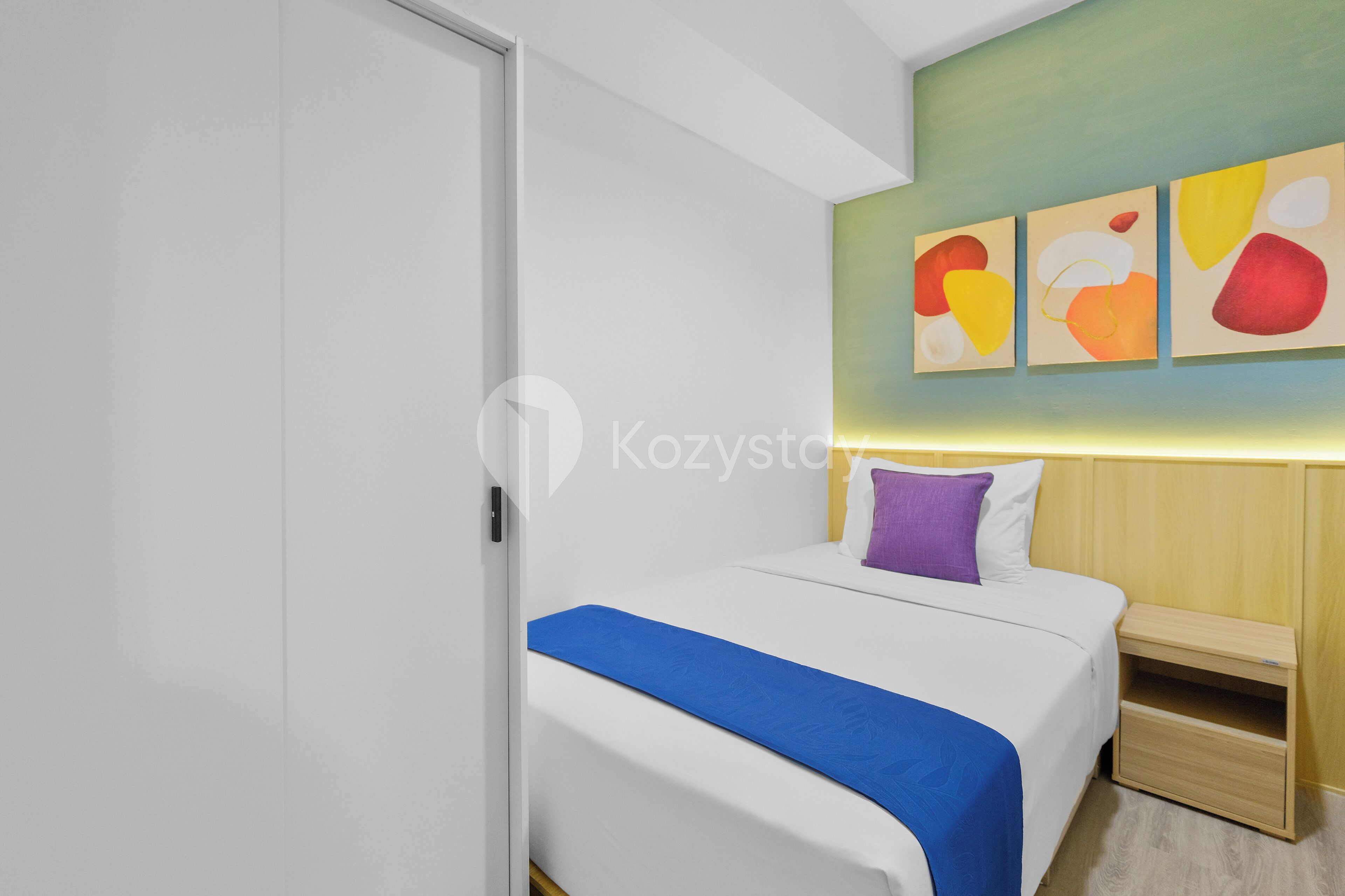 Una habitación de hotel moderna con una cama, una mesita de noche y una pared con arte abstracto.