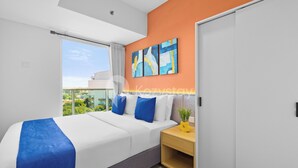 Una habitación de hotel moderna con una cama grande, una mesita de noche, un cuadro y vistas al exterior.