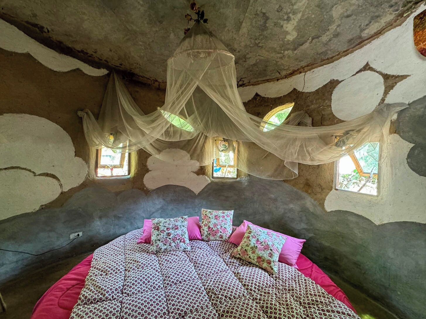 A bedroom with a bed, a window, and a decorative canopy.