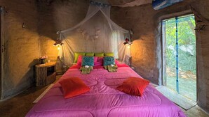 Un dormitorio con una cama grande, dosel, mesita de noche y una ventana.
