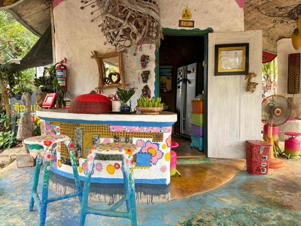A colorful, rustic kitchen with a bar area, a refrigerator, and various kitchen utensils.