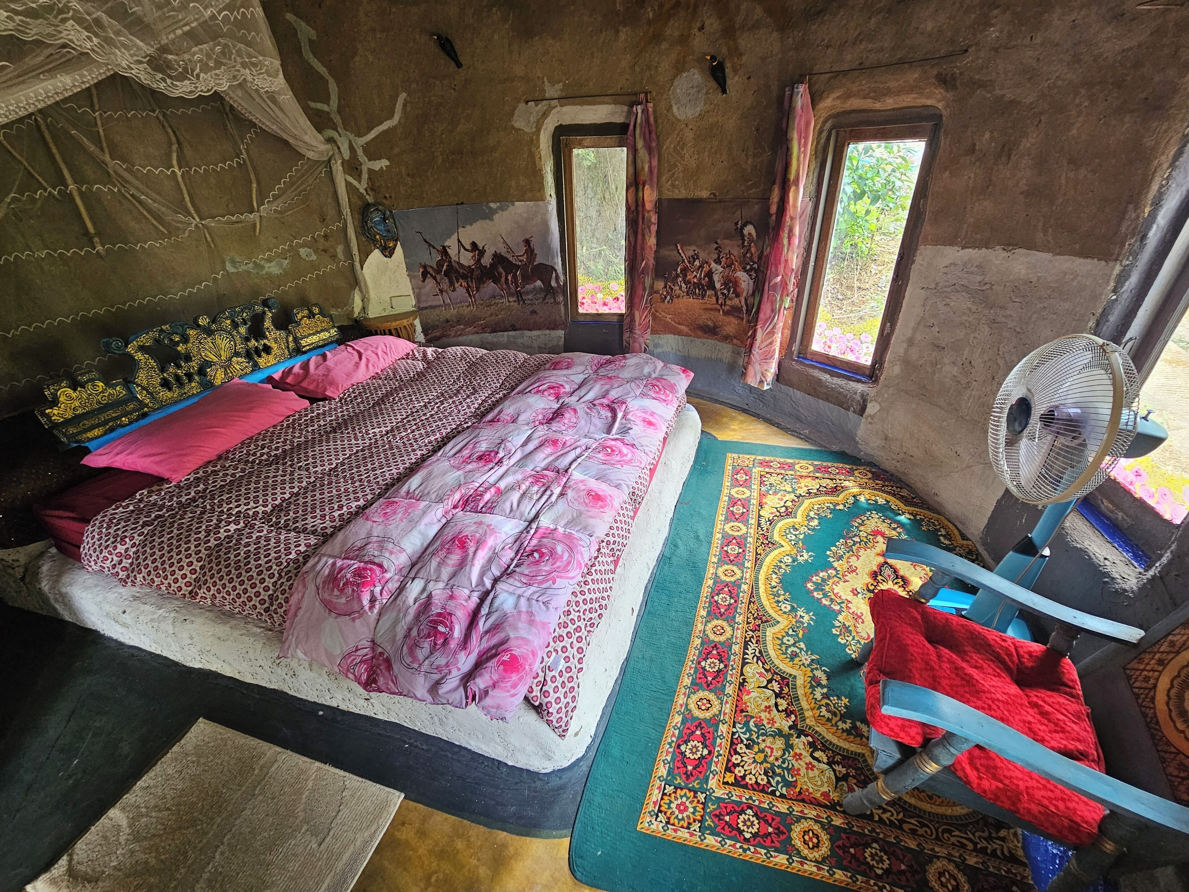 A room with a bed, a fan, a window, and a door.