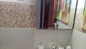 Ένα μπάνιο με έναν λευκό νιπτήρα, μια τουαλέτα και έναν καθρέφτη.