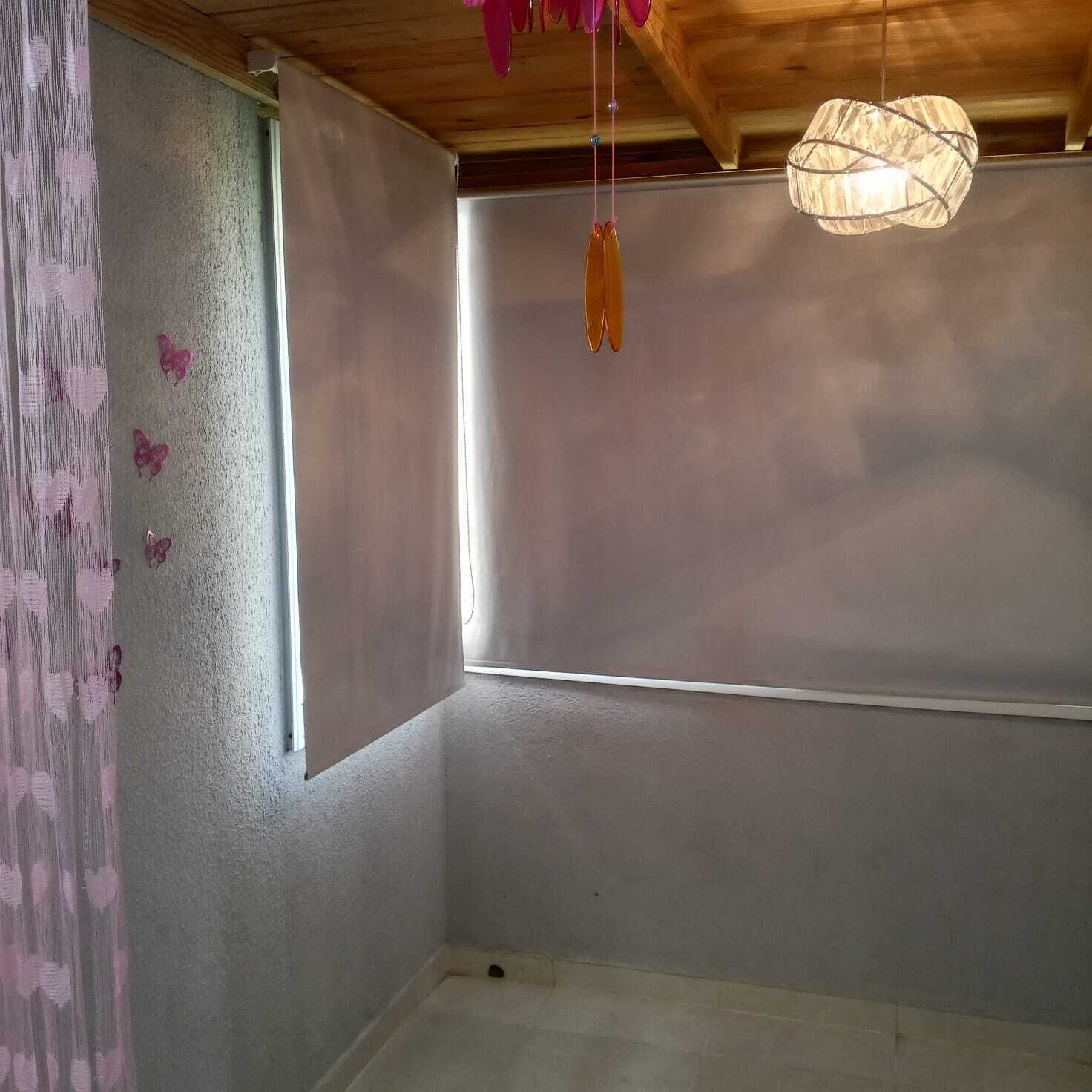 A room with a large window, a wooden ceiling, and a hanging light fixture.