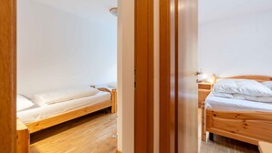 A room with two wooden beds, a wooden wardrobe, and a nightstand with a lamp.
