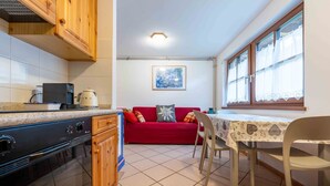 A compact kitchen with wooden cabinets, a stove, and a dining area with a table and chairs.
