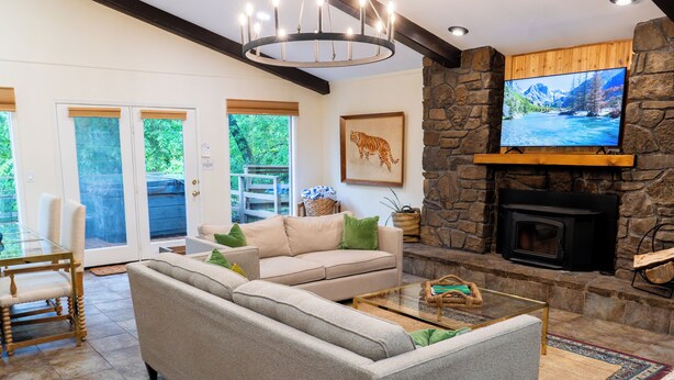 A living room with a stone fireplace, a television mounted on the wall, and a sofa with cushions.