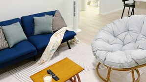 Un salon moderne avec un canapé bleu, un fauteuil gris et une table basse en bois.