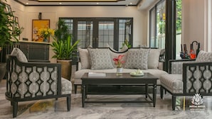 A modern hotel lobby with a sofa set, a coffee table, and a large potted plant. - Royal Hotel - Vinhomes Ocean Park 3 (Nghia Tru)