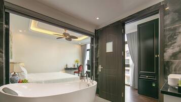 Une salle de bain moderne avec une baignoire sur pieds, un ventilateur de plafond et une vue sur la chambre à coucher.