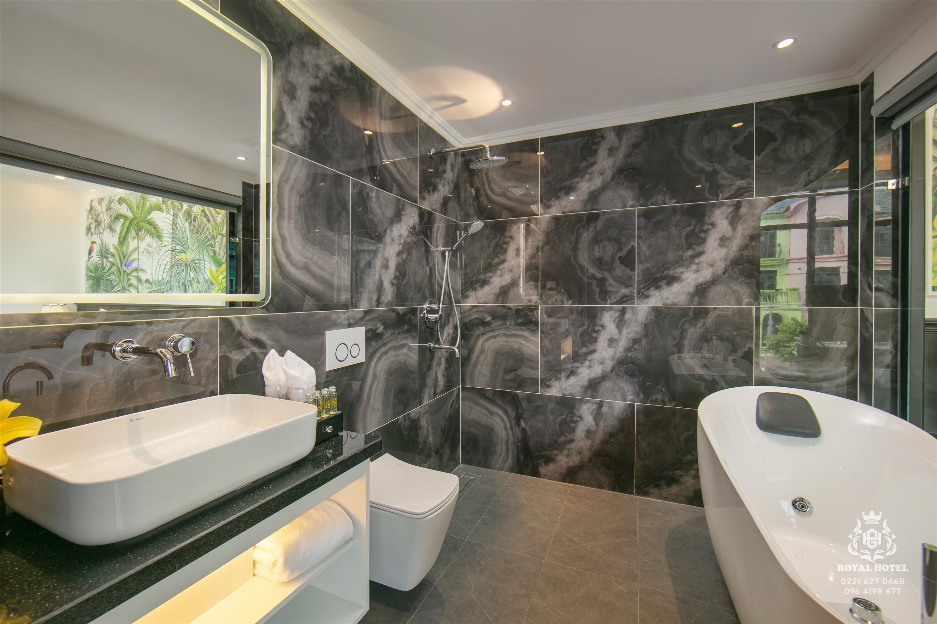 A modern bathroom with a large mirror, a double sink, and a separate bathtub.