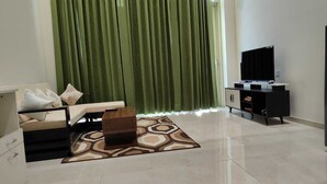 A modern living room with a sofa, a small table, a cabinet with a flat-screen TV, and a patterned rug. - Cozy Duplex Loft with WiFi and AC in amazing Gurugram (Gurugram)