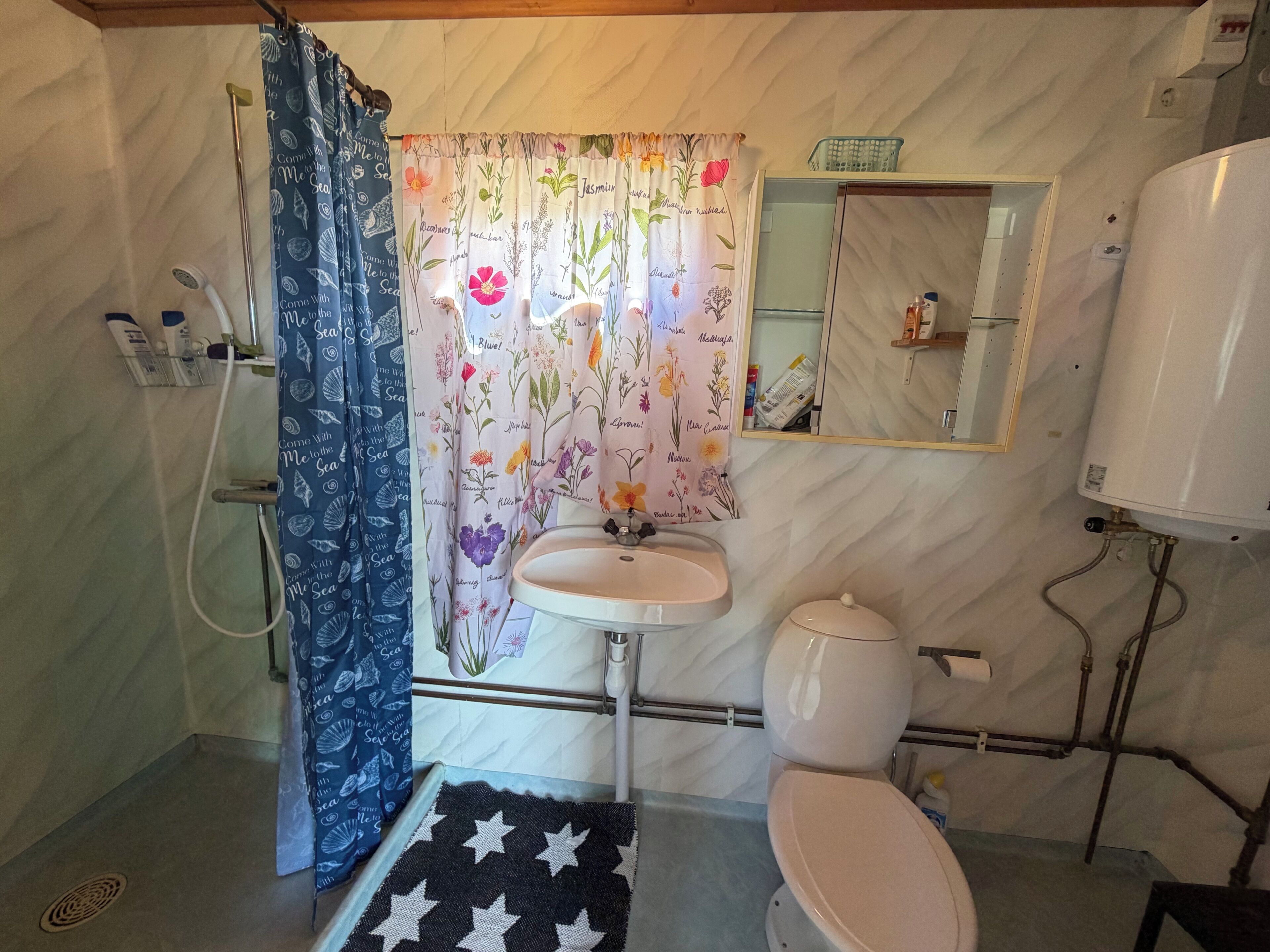 Un baño con cortina de ducha, lavamanos, inodoro y espejo.