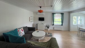 Una sala de estar moderna con un sofá gris, una mesa de centro blanca y un televisor montado en la pared.
