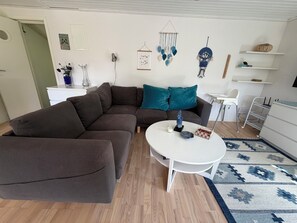 A modern living room with a sectional sofa, a white coffee table, and a patterned rug.