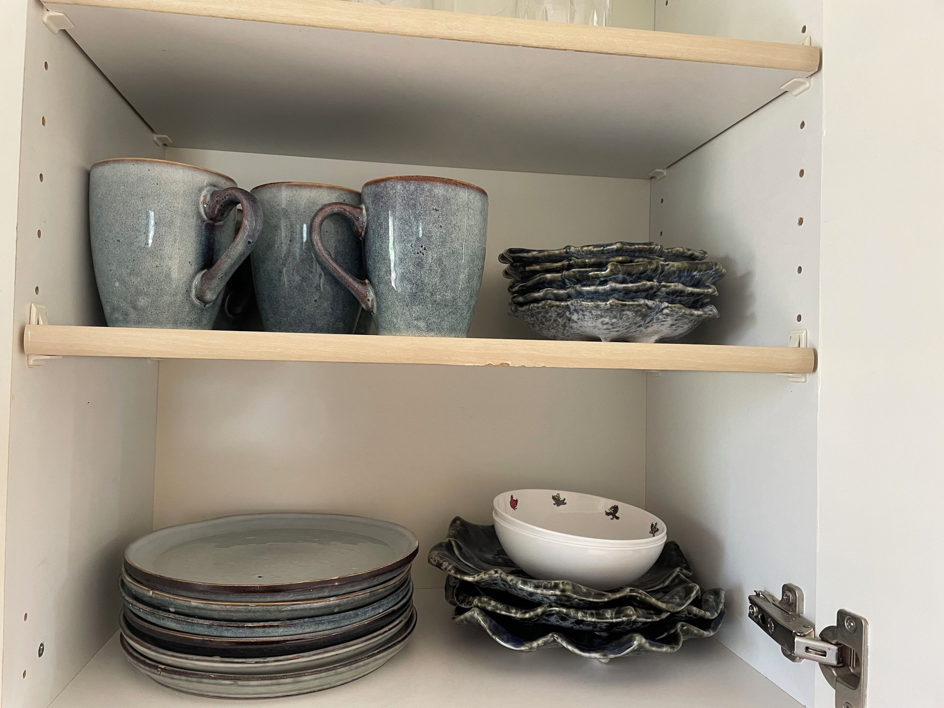 Una estantería con tazas de cerámica, platos y un cuenco decorativo.