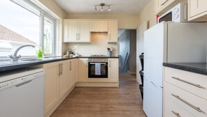 A compact kitchen with a dishwasher, oven, and microwave. - Charming 2-Bed Detached Home in Radyr (Cardiff)