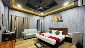 Una habitación de hotel moderna con cama, escritorio, sillón, sofá y ventilador de techo.