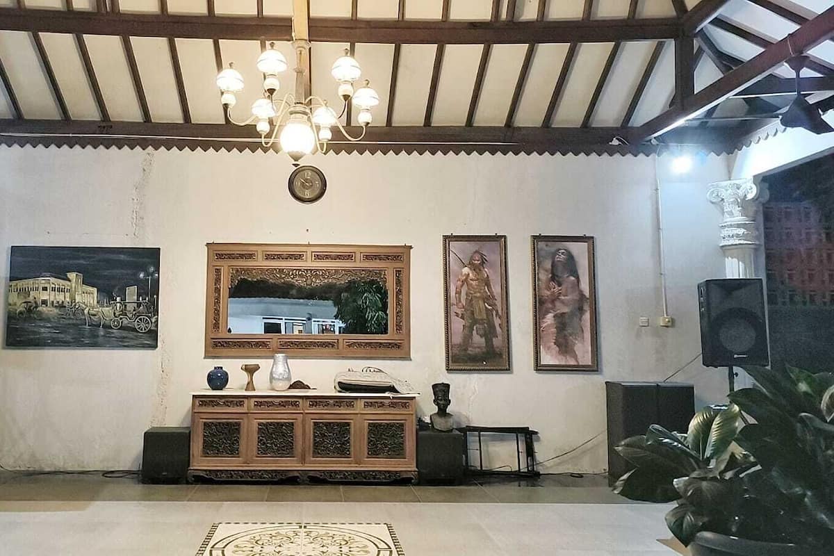 A room with a wooden ceiling, a chandelier, a large mirror, and framed pictures on the wall.