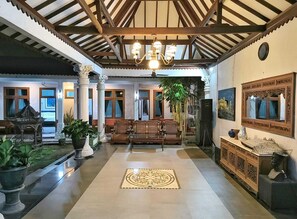 Eine geräumige Lobby mit hoher Decke, Holzbalken, einem zentralen Kronleuchter und einer Sitzecke mit Sofas.