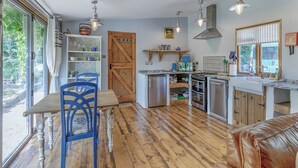 Eine Küche mit Holzboden, einem Esstisch mit blauen Stühlen und einer Holztür.