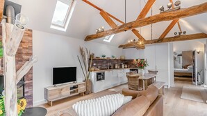 A modern living room with a television, sofa, and dining area. - Weston Cottage - UK50016 (Woking, near Guildford)