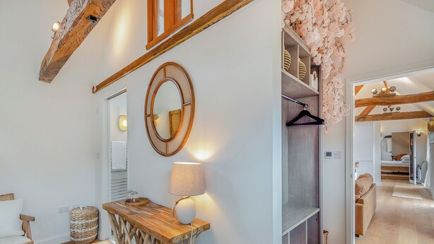 A modern interior with a wooden table, a hanging mirror, and a wall-mounted lamp. - Weston Cottage - UK50016 (Woking, near Guildford)