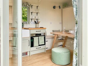 A compact kitchenette with a built-in oven, a small countertop, and a wooden table.
