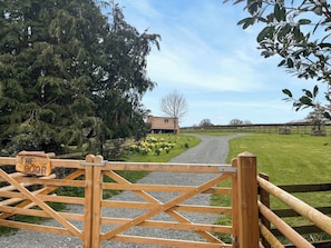 A wooden gate with a sign reading 'THE COOP' leading to a grassy area with a building in the background.