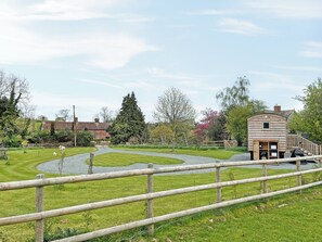 Un bâtiment rustique en bois, doté d’une petite fenêtre, entouré d’une pelouse bien entretenue et bordé d’un chemin de gravier.