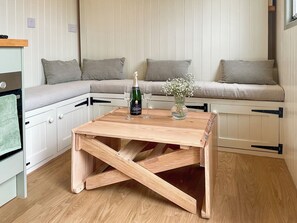 A cozy room with a wooden table, a bottle of wine, and a vase of flowers on a bench. - 1 bedroom accommodation in Southtown, nr Illminster (Southtown, nr Illminster)