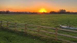 A grassy field with a wooden fence and a metal structure. - 1 bedroom accommodation in Southtown, nr Illminster (Southtown, nr Illminster)