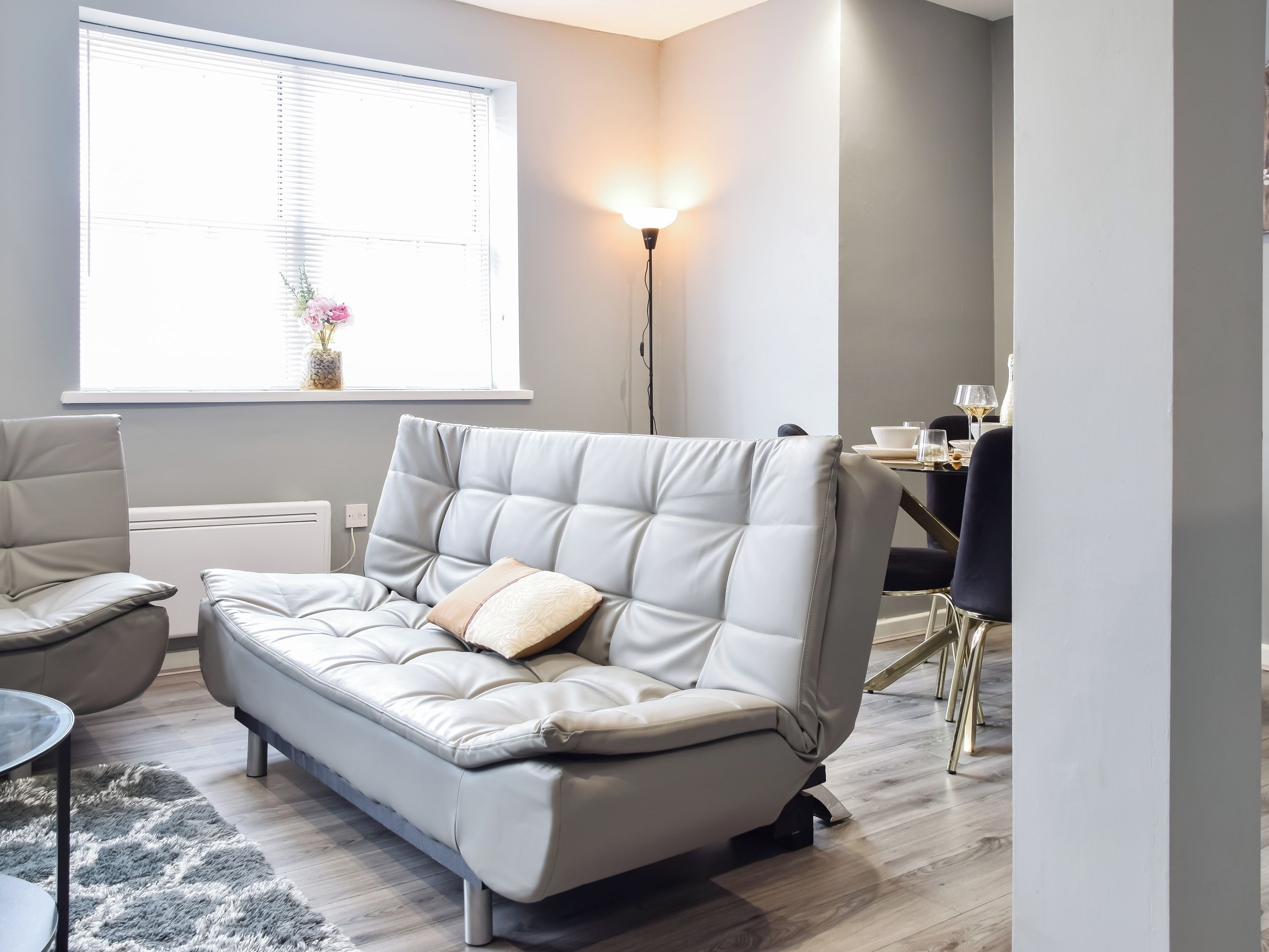 A modern living room with a sofa, a dining table, and a floor lamp.