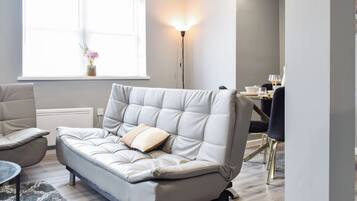 A modern living room with a sofa, a dining table, and a floor lamp.