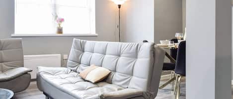 En moderne stue med sofa, spisebord og gulvlampe.