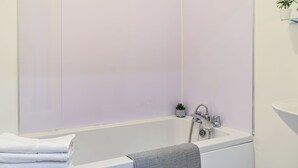 Un baño con bañera, lavamanos y espejo.
