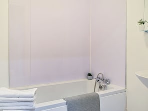 Une salle de bain avec une baignoire, un lavabo et un miroir.