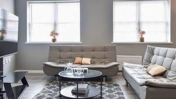 A modern living room with two sofas, a coffee table, and a TV.