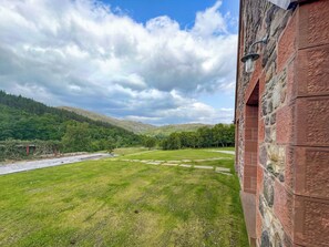 A view from a stone building with a stone wall and a metal light fixture.