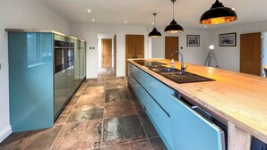 Una cocina moderna con una isla central, armarios azules y encimera de madera.